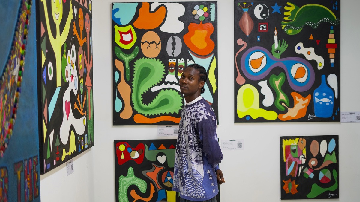 A wall of Ìpadàbọ̀ hung at Nike Art Gallery, with a visitor looking on