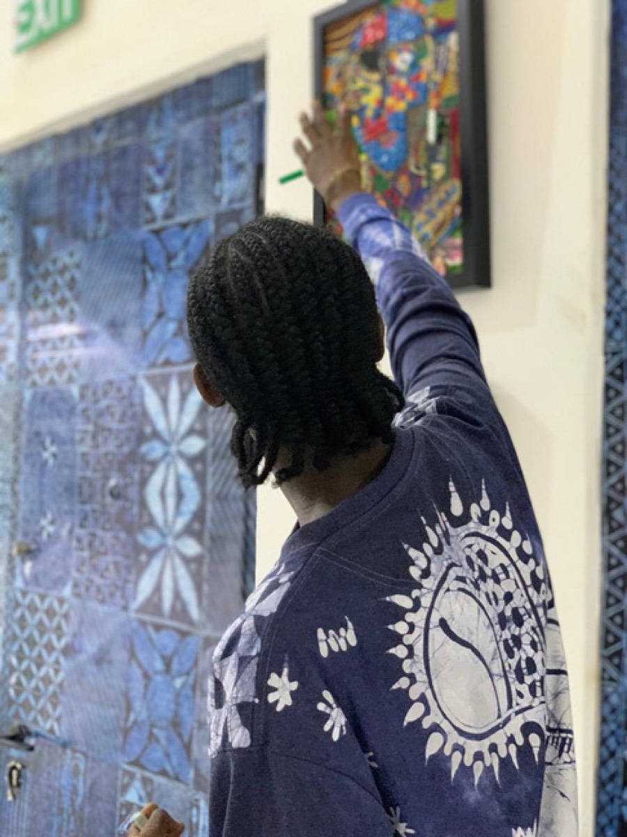 A visitor reaching toward the fabric works on the wall